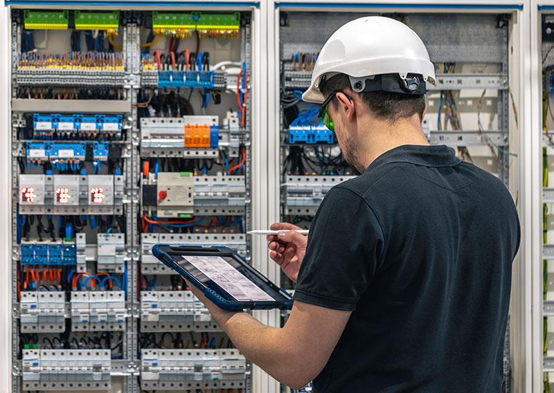 An engineer inspecting a motor control center (MCC) panel for variable frequency drive optimization.