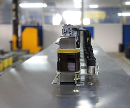 A long batch of three-phase sine wave filters aligned on the factory assembly line for quality inspection.