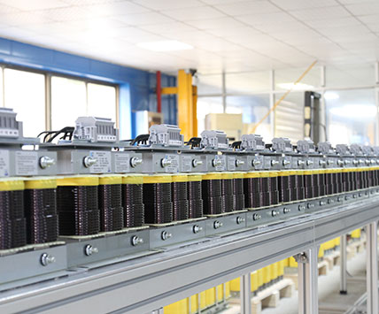 A long batch of three-phase sine wave filters aligned on the factory assembly line for quality inspection.
