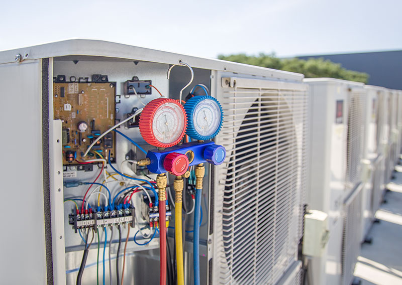 Commercial HVAC compressor units on a rooftop undergoing maintenance and harmonic filtering setup.