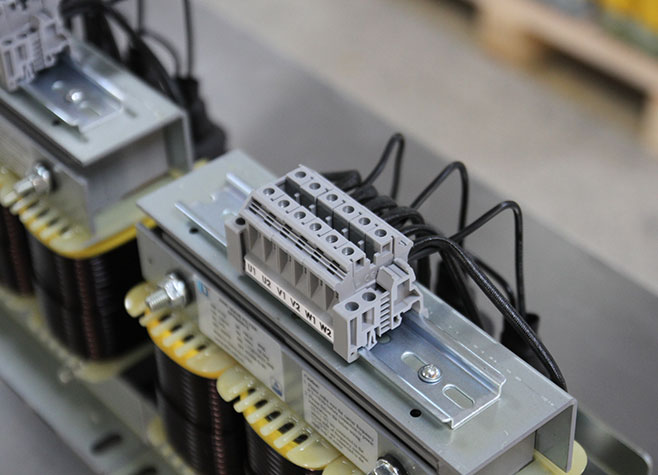 Close-up of screw terminals and wiring marks on a three-phase sine wave filter, showing compact design for switchgear panel mounting.