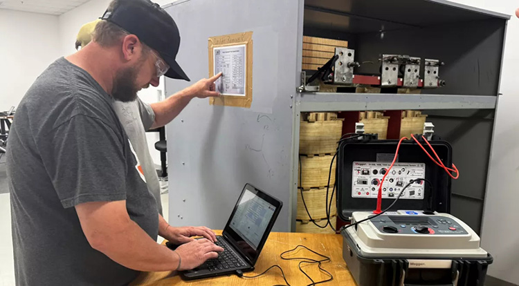 Technician reviewing test report data and parameters for dry-type transformers