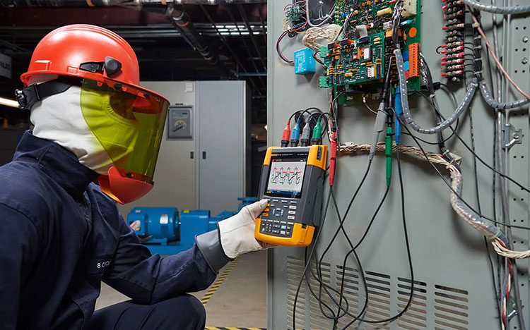 Engineer testing electrical harmonics using a portable power quality analyzer in an industrial setting